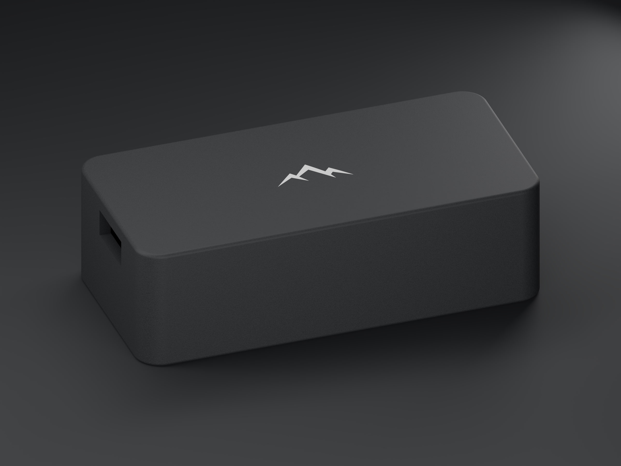 Three-quarter view of the NOMAE enclosure on a dark studio floor, the debossed mountain mark catching the key light