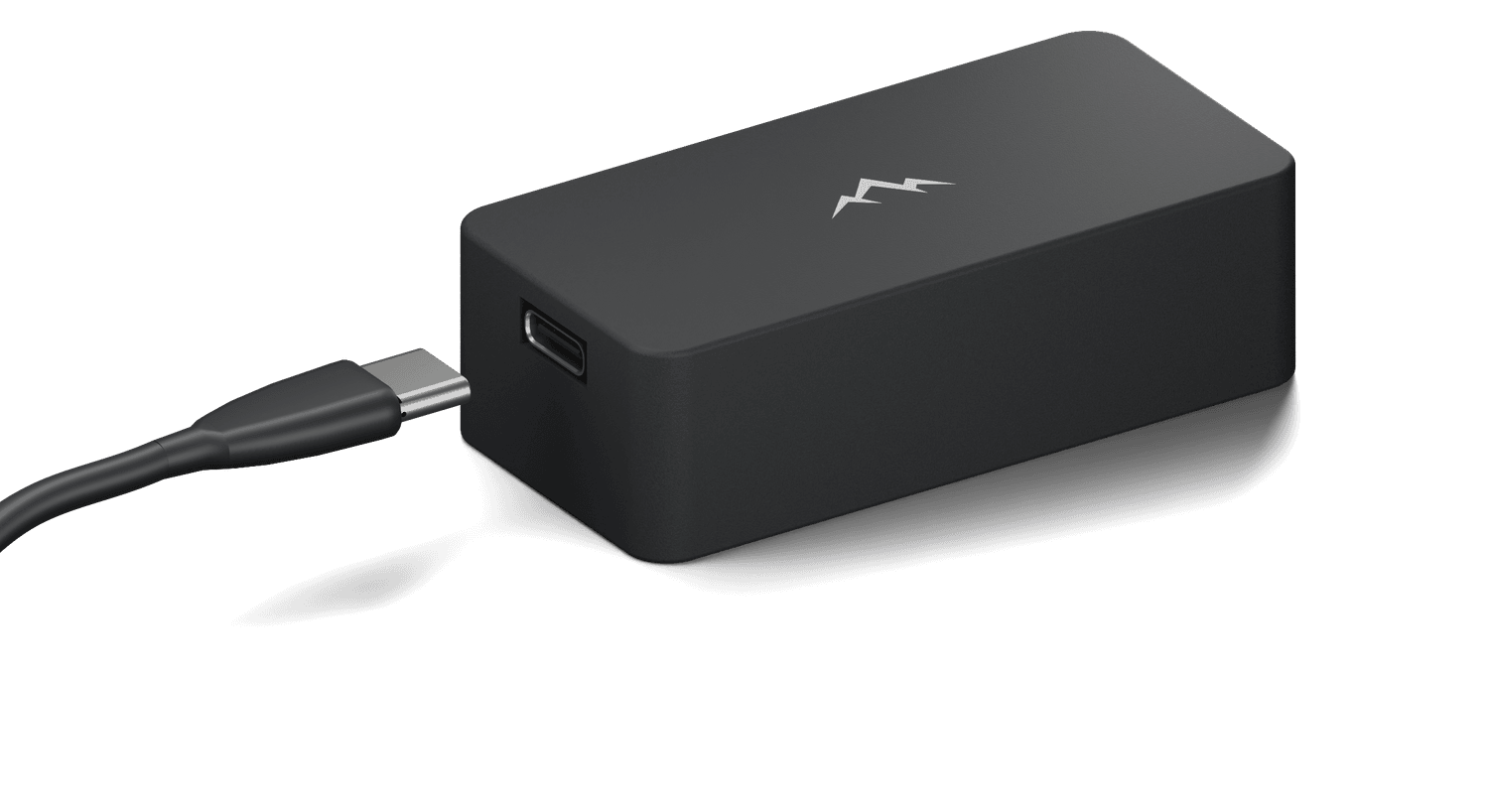 NOMAE, a matte black magnetic motion tracker with a debossed mountain mark on the lid, a USB-C cable at its open end